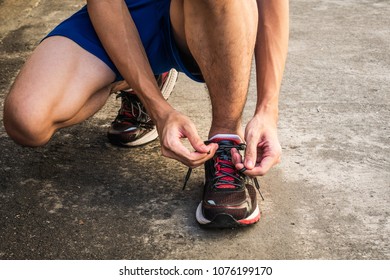 Male runner tying running shoes laces - Shutterstock ID 1076199170