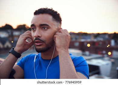 Male runner in urban setting adjusting earphones, close up - Powered by Shutterstock