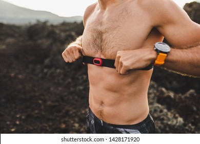 Male Runner Wearing Professional Chest Heart Rate Monitor And Preparing For Trail Running Outdoors. Topless Body Close-up And Smart Watch Or Fitness Tracker On Hand.