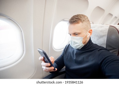 Male With Safe Mask Passenger Of Airplane Use Mobile Phone In Chair. Concept Travel Covid.