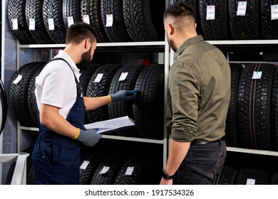 Male Salesman Showing Wheel Tires To Caucasian Man Customer At Car Repair Service And Auto Store Shop, They Are Discussing And Talk About Advantages Of Tires