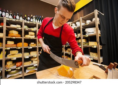 Male Salesperson Cutting Cheese In Store