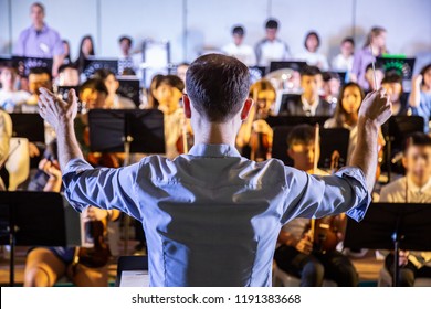 Male school conductor conductiong his student band to perform music in a school concert - Shutterstock ID 1191383668