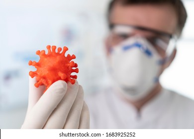 Male scientist or virologist with mask holds 3d model of covid-19 corona virus in hand - Powered by Shutterstock