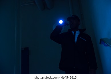 Male Security Guard In Black Uniform Holding Flashlight