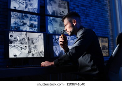 Male Security Guard With Portable Transmitter Monitoring Modern CCTV Cameras Indoors