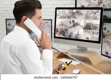 Male security guard talking by telephone near monitors at workplace