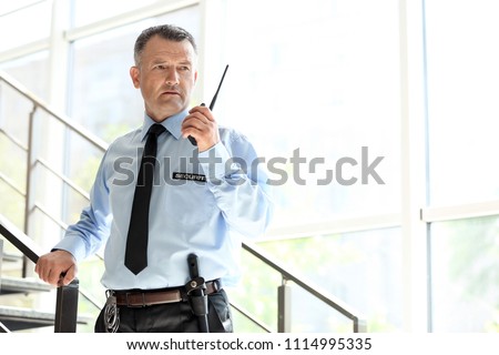 Male security guard using portable radio transmitter indoors