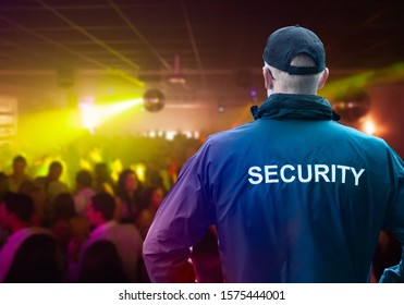 Male Security Officer Wearing Cap Standing In Night Club With His Hands On Hips