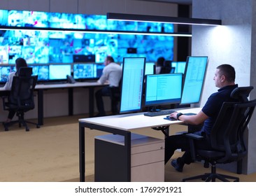 Bediener von männlichen Sicherheitsbetreibern, die in einem Kontrollraum für das Datensystem tätig sind Technische Bedienungspersonal An der Workstation mit mehreren Bildschirmen arbeiten, Sicherheitswachstelle, die auf mehreren Monitoren arbeiten Männliche Computeroperie