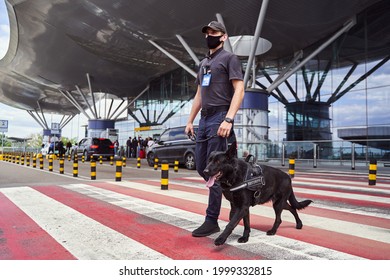 Male Security Worker With Police Dog Crossing The Road At Airport