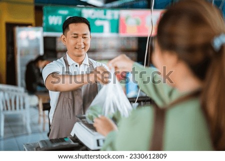 male seller putting the plastic bag on the scale to scalling it on cashier