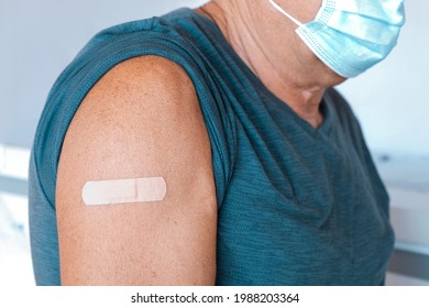 Male Senior In Face Mask After Receiving COVID-19 Vaccine. Elderly Man Feeling Good On Getting Coronavirus Vaccine. Covid Vaccination For Older People. Senior Patient Showing Arm With Bandage, Patch.