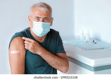 Male Senior In Face Mask After Receiving COVID-19 Vaccine. Elderly Man Feeling Good On Getting Coronavirus Vaccine. Covid Vaccination For Older People. Senior Patient Showing Arm With Bandage, Patch.