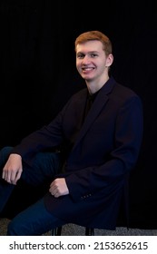 Male Senior Highschool Student Posing For Senior Photoshoot.  Auburn Red Hair And Wearing Sportscoat Isolated In Black Background.