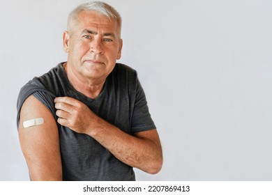 Male Senior Smiling after Receiving Vaccine. Old Man Showing Arm with Bandage, Patch after Vaccine from COVID-19 or Monkeypox. Covid, Monkey Pox Vaccination for Older People. Gray Studio Background. - Powered by Shutterstock