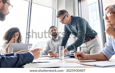 Male serious caucasian ceo executive mentor businessman leader with diverse colleagues team, managers group at meeting. Multiethnic professional business people discussing project plan in boardroom.