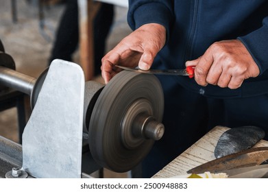 male sharpener sharpens a knife blade on a knife sharpening machine in workshop - Powered by Shutterstock