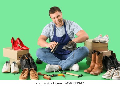 Male shoemaker brushing boot on green background - Powered by Shutterstock