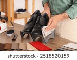 Male shoemaker cleaning shoes in repair shop, closeup