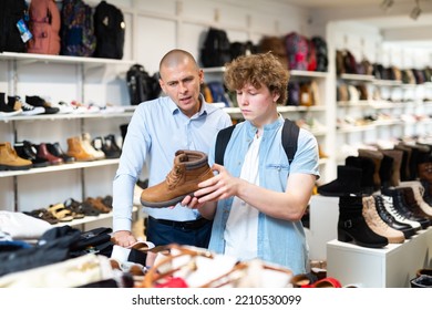 Male Shop Assistant Consulting Teenager In Shoes Shop