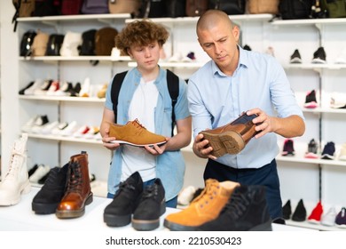 Male Shop Assistant Consulting Teenager In Shoes Shop