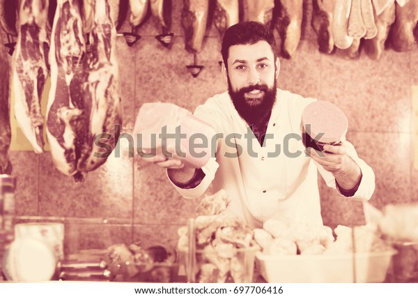 Male Shop Assistant Demonstrating Meatloaf In Butcher`s Shop