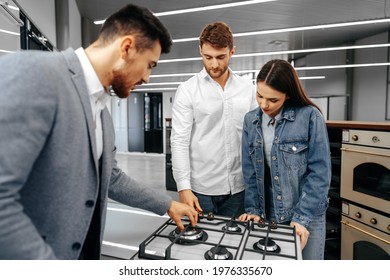 Male Shop Assistant Helps Young Couple To Choose New Home Appliance