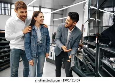 Male Shop Assistant Helps Young Couple To Choose New Home Appliance