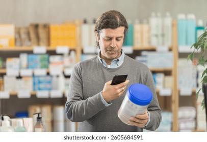 Male shopper in autumn clothes scans QR code on label of food for small children using her smartphone