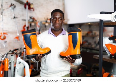 Male Shopper Chooses Rubber Boots At A Garden Tool Store