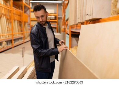 Male Shopper In A Lumber Store Next To Plywood And OSB Panels