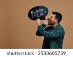 Male shopper shouting while holding Black Friday speech bubble. Copy space.