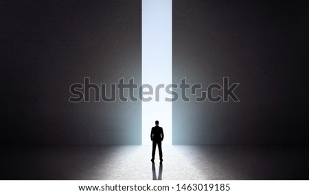 Male silhouette in front of huge opening concrete doors with blue light opening, panorama, copy space