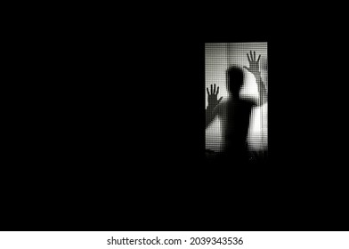 Male Silhouette Of A Person Behind A Glass Backlit With Raised Hands. Concept Shadows And Terror. Halloween. Fear