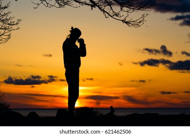 male silhouette standing and asking for something, praying gesture during bright sunset. man holding hands in thoughtful pose.  - Shutterstock ID 621462506