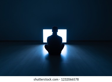 The Male Sitting In The Dark Room In Front Of A Television