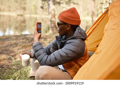 Male Sitting On Nature And Taking Video Of Lake. Chilling With Cup Of Coffee. Sleepover In Tent On Fresh Air. Camping Alone, Make Time For Travelling, Open New Horizons Concept