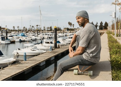 Male skater sitting on longboard in port - Powered by Shutterstock