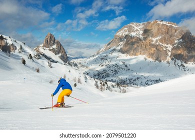 Male skier in blue and yellow clothes on slope with mountains in the background at Cortina d'Ampezzo Col Gallina Sella Ronda skiing resort area Dolomiti Italy