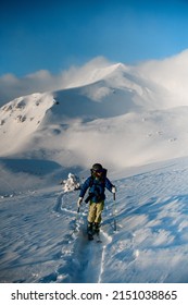 Male skier walking on deep white powdery snow path of snow-capped mountain Shpytsy in Ukraine. Freeride and ski touring concept