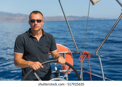 Male Skipper At The Helm Sailing Boat, Controls Ship During Sea Yacht Race. Luxery Vacations, Adventure, Travel.