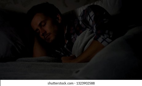 Male Sleeping Alone In Dark Room At Night, Comfortable Mattress And Pillows