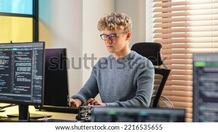 Male Software Engineer Coding On Desktop Computer in Creative Office Space. Young Caucasian Man Applying His Programming Skills in Innovative Technological Startup. Junior Developer Working.
