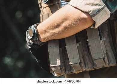 Male soldier wearing a bulletproof vest and a shirt with short sleeves. On hand watches.