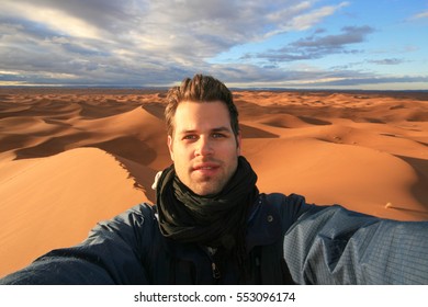 Male Solo Traveler Taking Selfie At Dunes In Sahara Desert, Morocco.