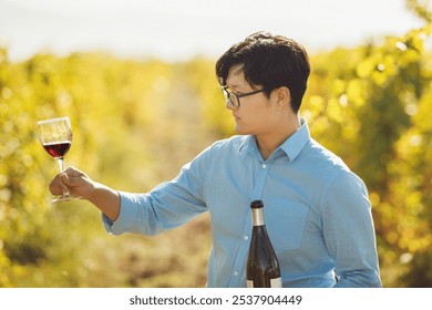 Male Sommelier Holding Glass of Red Wine Standing in Vineyard - Powered by Shutterstock