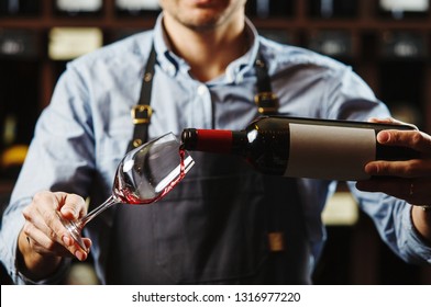 Male sommelier pouring red wine into long-stemmed wineglasses. - Powered by Shutterstock