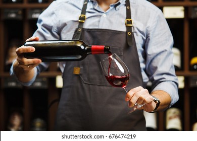 Male sommelier pouring red wine into long-stemmed wineglasses. - Shutterstock ID 676474219