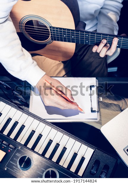 male songwriter writing a song\
with laptop computer and keyboard on desk. songwriting\
concept